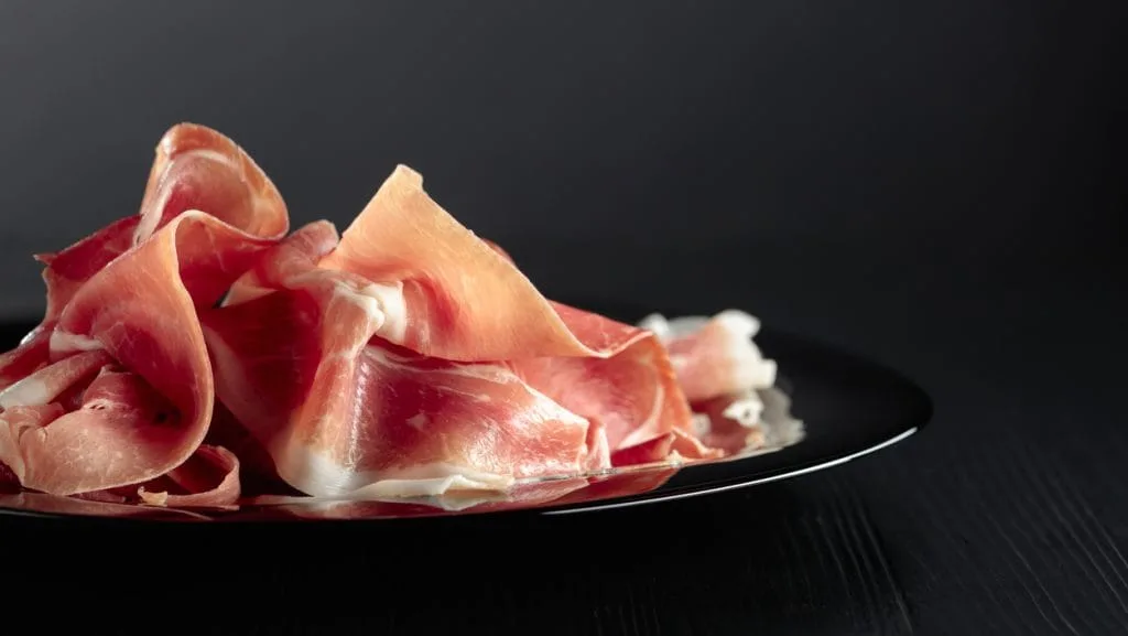 Italian prosciutto or Spanish jamon on a black plate.
